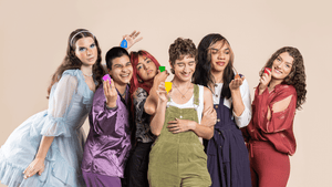 Gender diverse people holding up multi-colored June Menstrual Cups, wearing rainbow colors for Pride Month.